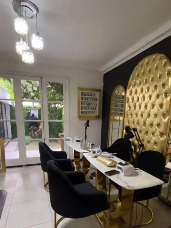 Zona de manicure con mesas de mármol y respaldo capitoné dorado